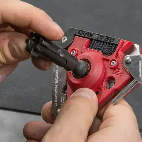 Multitool rusznikarski Real Avid Carbon Boss AR-15 leżący obok dedykowanej kabury transportowej z czarnego nylonu balistycznego.